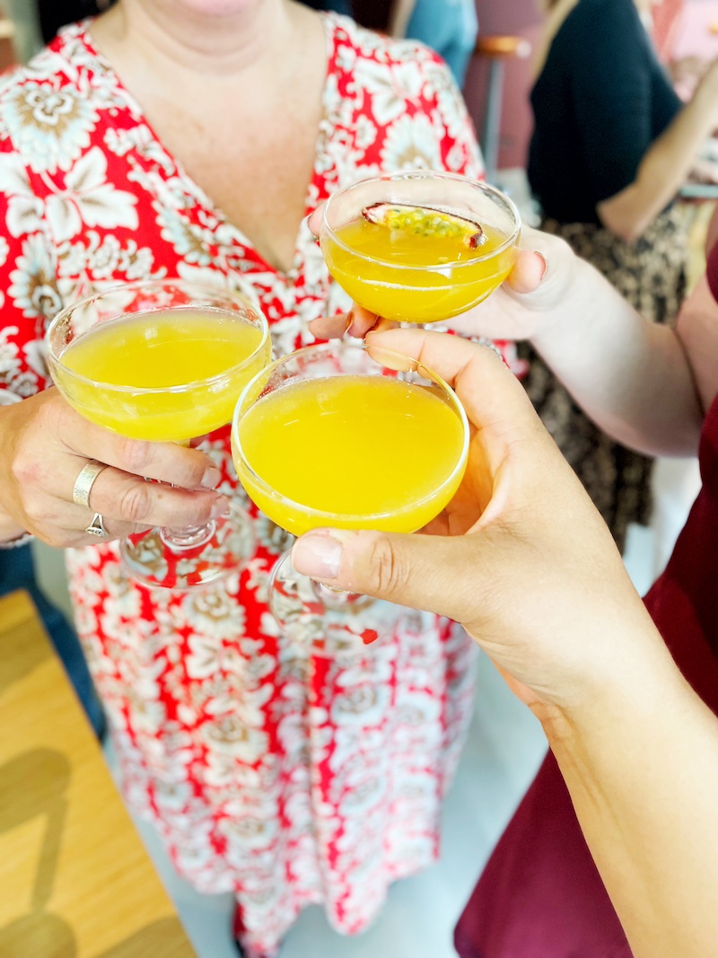 Three people toasting with a yellow cocktail